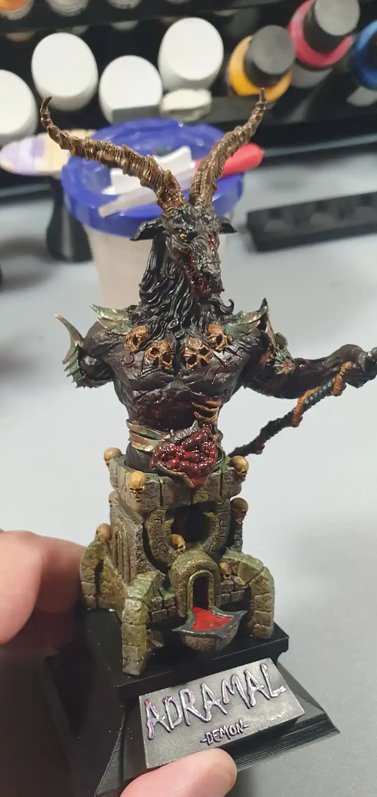 A highly detailed, painted miniature of a demonic figure with large curved horns, a goat-like head, and a muscular torso…