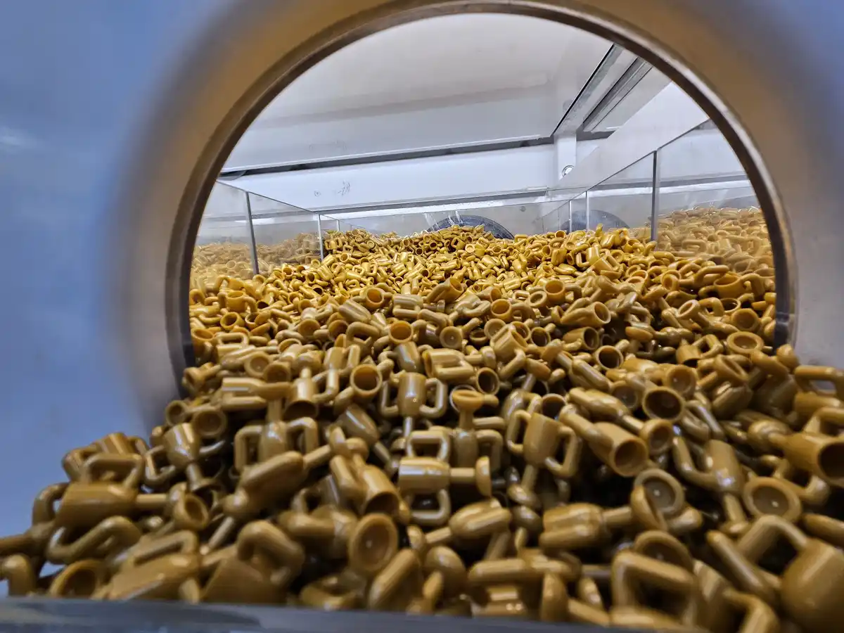 A close-up view through a circular opening into a large industrial machine filled with a massive pile of tan-colored Lego…