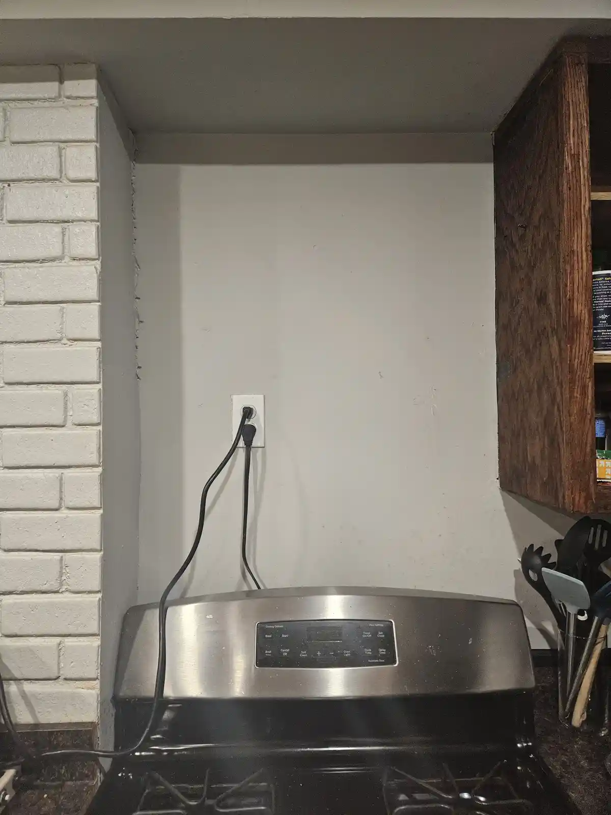 A close-up photo of a stainless steel oven with a black control panel, positioned under a white wall with a single…