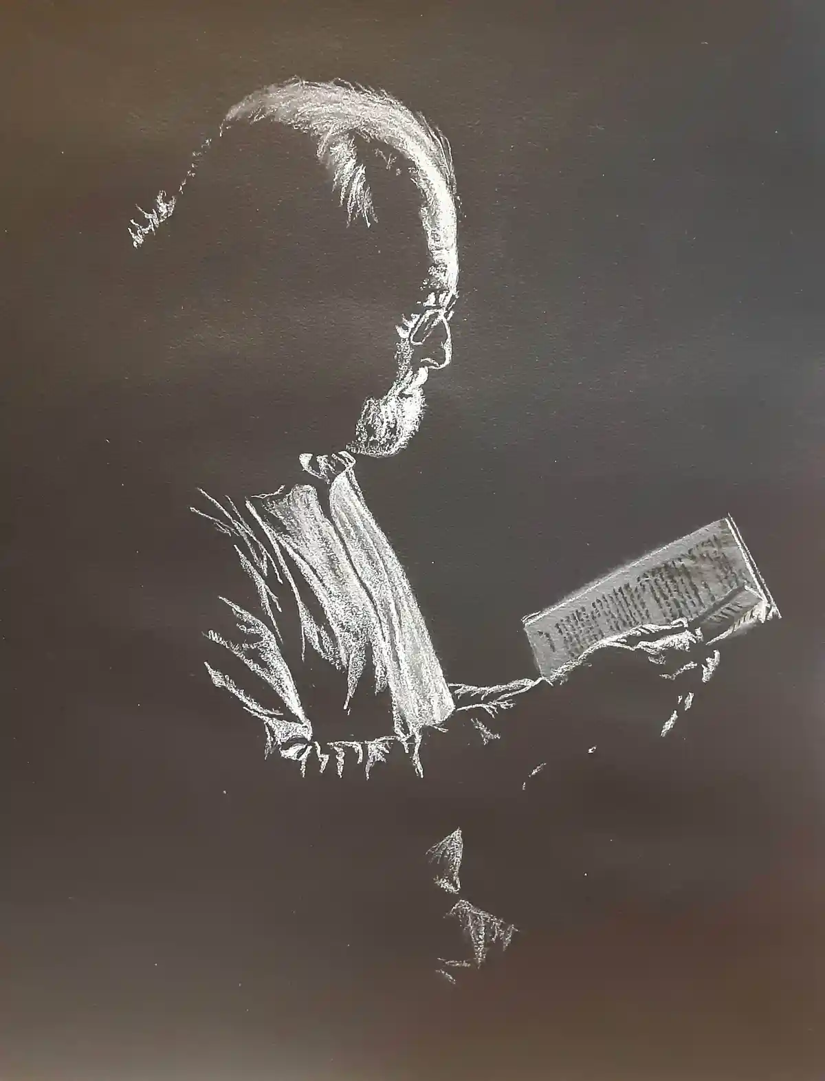 A chalk drawing on a dark surface depicts a person in profile, wearing a jacket and holding a book tilted away from their…