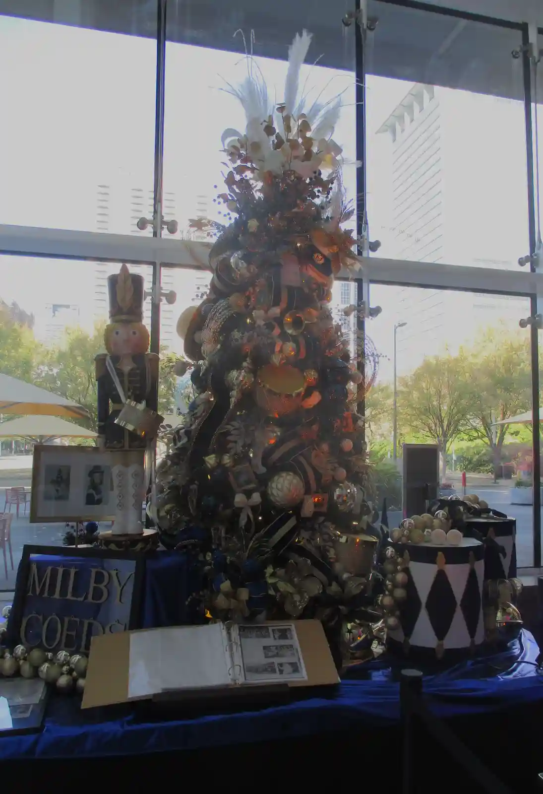 A heavily decorated Christmas tree with gold, black, and white ornaments, feathers, and musical instruments like drums…