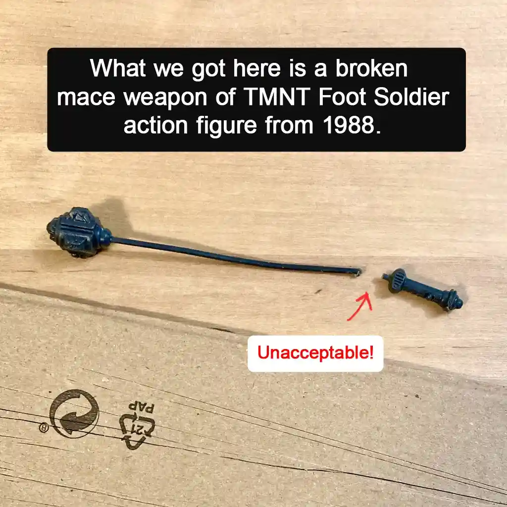 A broken blue plastic mace weapon from a 1988 Teenage Mutant Ninja Turtles Foot Soldier action figure lies on a wooden…