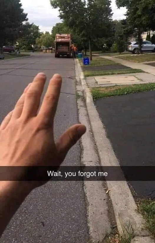 A person's hand is extended toward a garbage truck in a residential street, as if trying to catch up or be included. The…