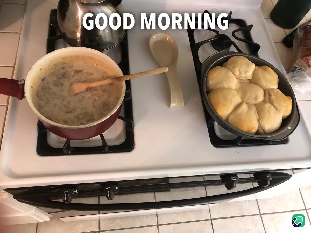 A white stovetop with black burners holds a red pot of creamy sausage gravy with a wooden spoon, a ceramic spoon rest, and a…