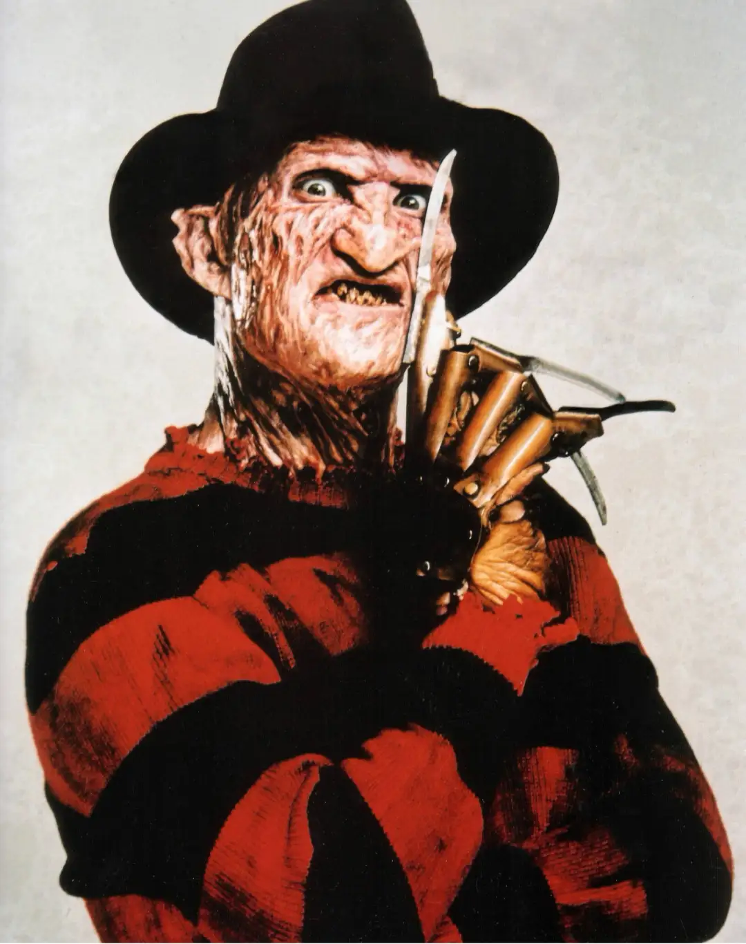 A close-up of the horror movie character Freddy Krueger, recognizable by his burnt, scarred face, black fedora, and iconic…