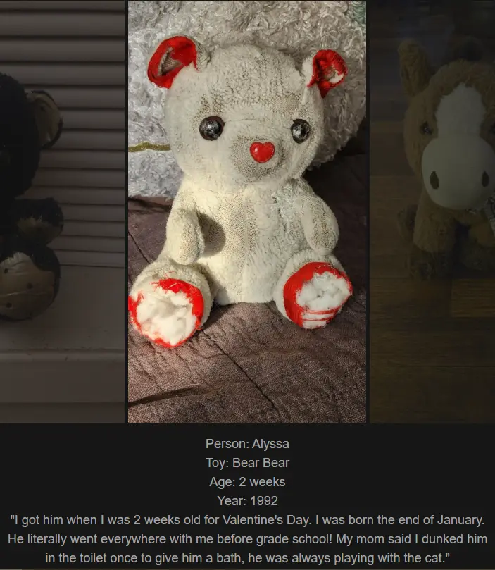 A heavily worn, white teddy bear with red accents on its ears, nose, and paws sits on a brown fabric surface. The bear's…