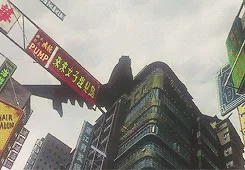 A low-angle shot of a city street with tall buildings, where a large red banner with the text 'air pump' is hanging from a…