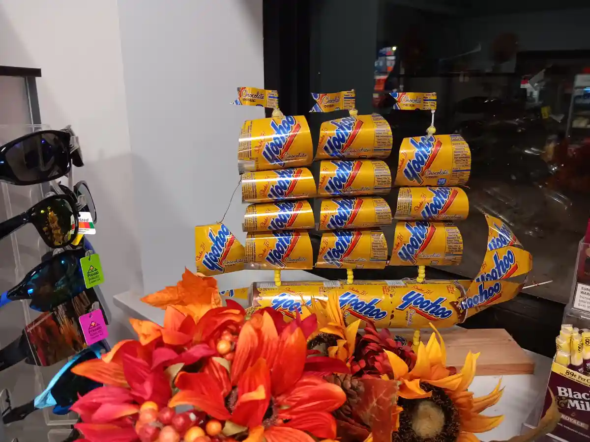 A decorative display made of Yoo-hoo chocolate drink cans arranged to resemble a ship with sails and a hull, positioned…