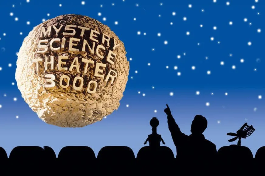 A silhouette of a person and two robots sitting in theater seats, pointing up at a large, textured brain floating in a…