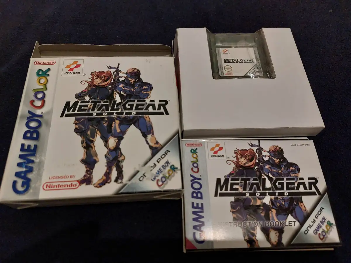 A photo shows the physical components of the Metal Gear Solid Game Boy Color game: the main game box, the instruction…