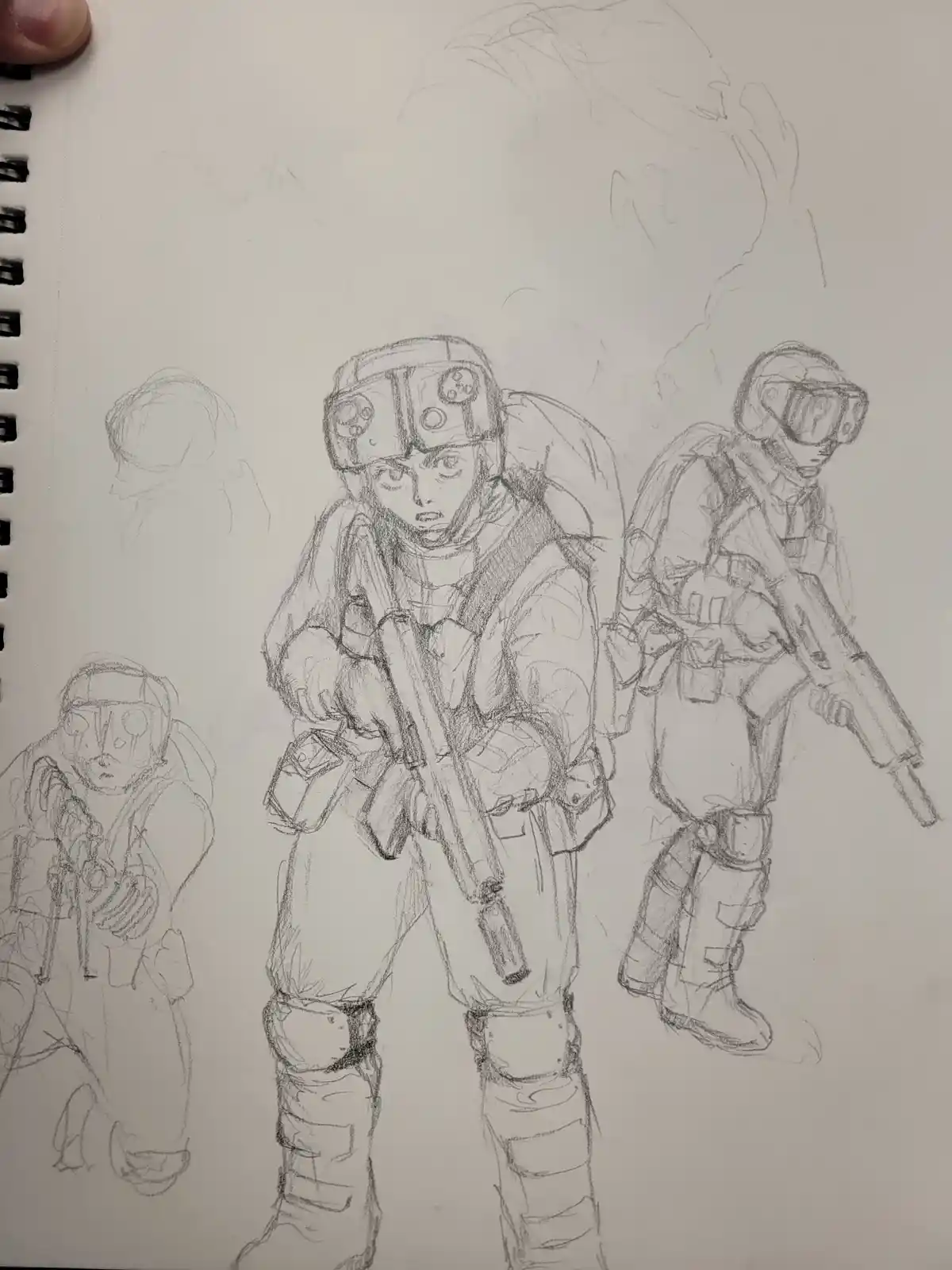 A pencil sketch on spiral-bound paper shows three figures in futuristic combat gear, one central figure holding a rifle…