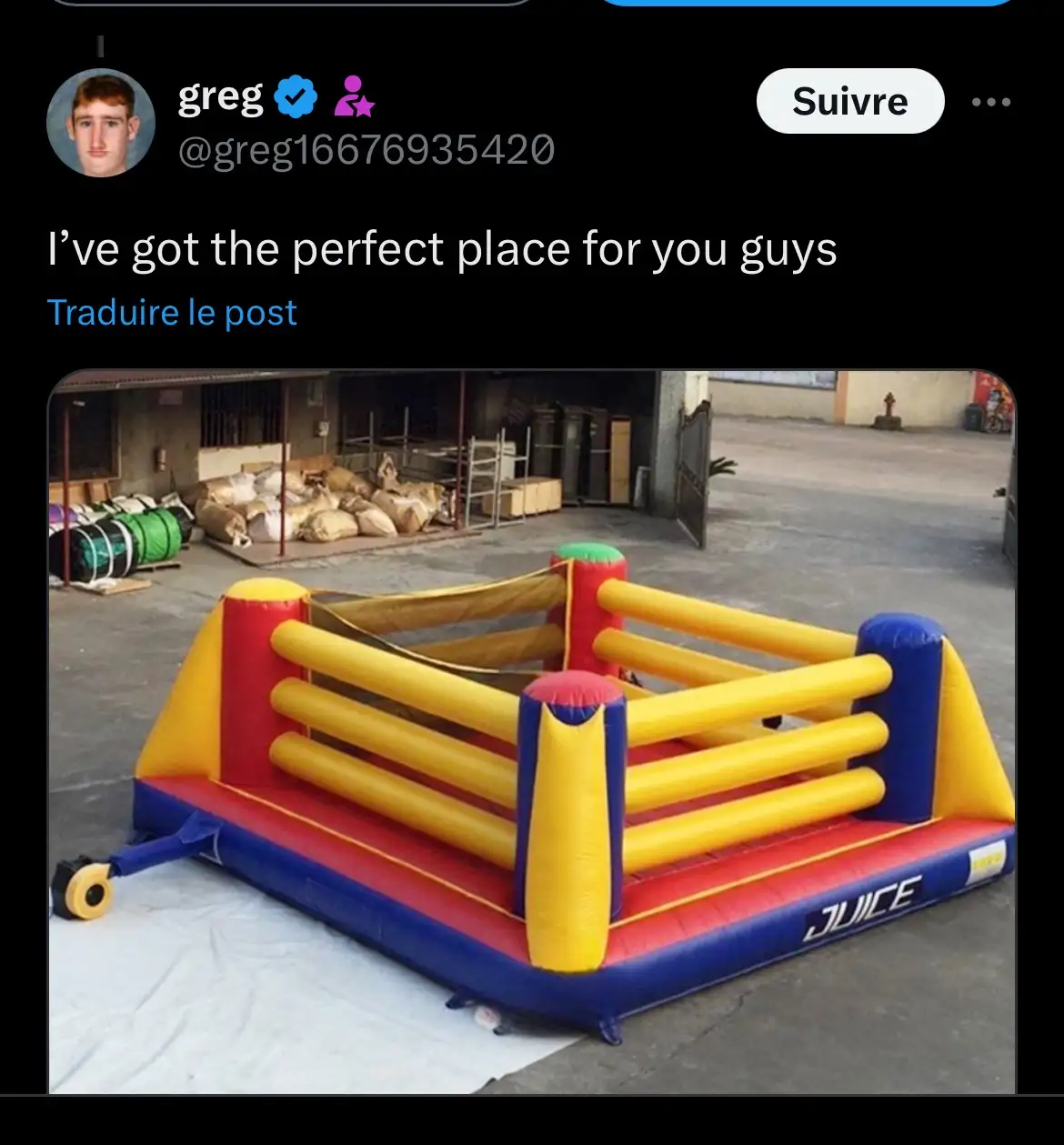 An image of a colorful inflatable boxing ring, primarily yellow, red, and blue, sitting on a white tarp in what appears to…