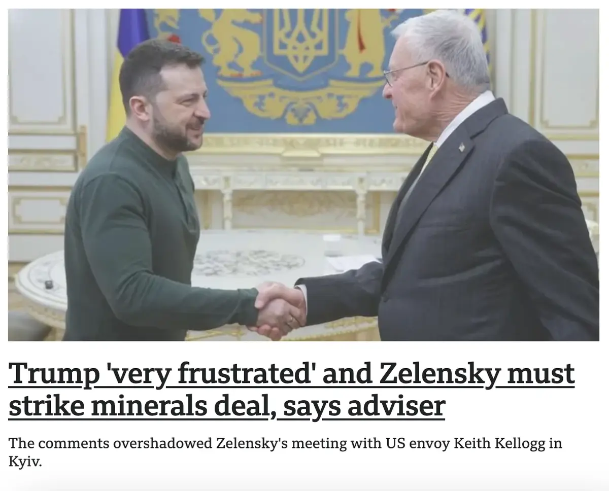 Two men shake hands in a formal room with a Ukrainian coat of arms behind them. The man on the left wears a dark green…