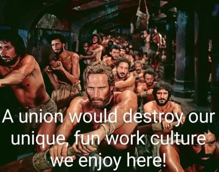 A still from the 1951 film 'Ben-Hur' shows a group of shirtless, muscular men in a crowded, dimly lit setting, likely a…