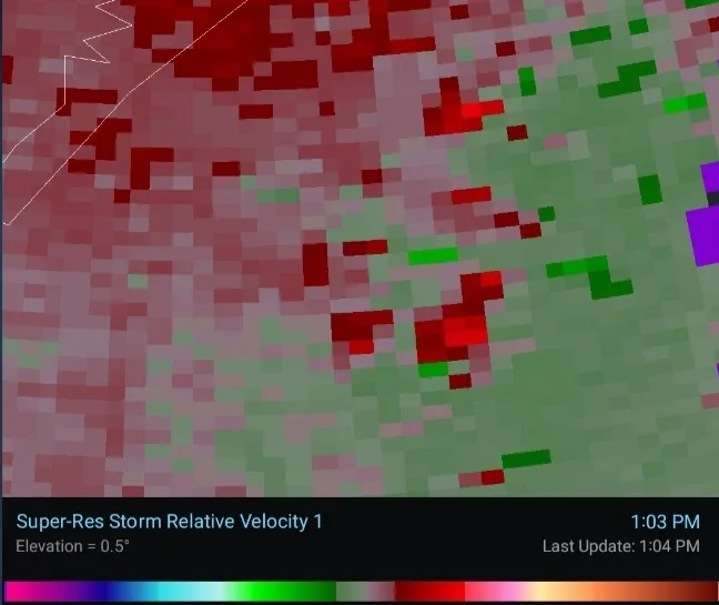 A weather radar image showing a storm with red and green pixelated areas indicating wind velocity, overlaid with text…