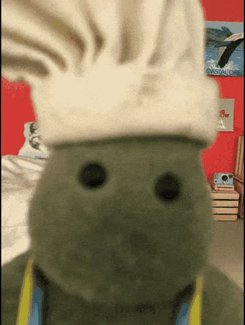 A green, plush, frog-like character wearing a white chef's hat and a yellow apron is shown in a six-panel grid. In the top…