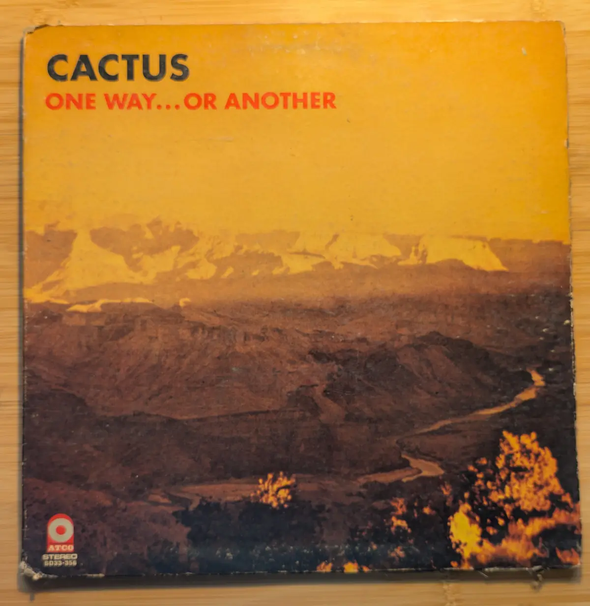 The image shows the cover of a vintage vinyl record by the band Cactus, featuring a desert landscape with mountains and a…