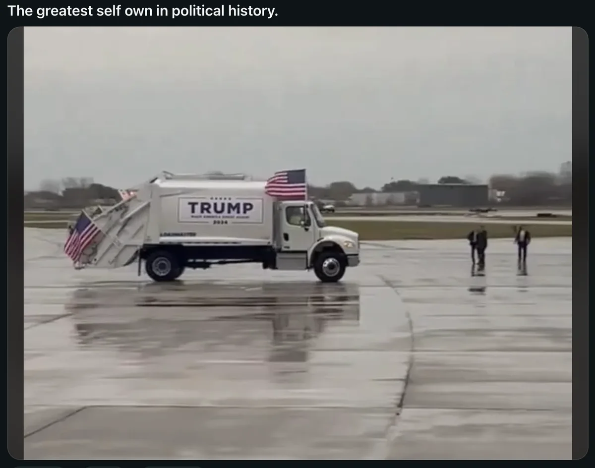 A white garbage truck with 'TRUMP MAKE AMERICA GREAT AGAIN 2024' written on its side and American flags attached to its rear…