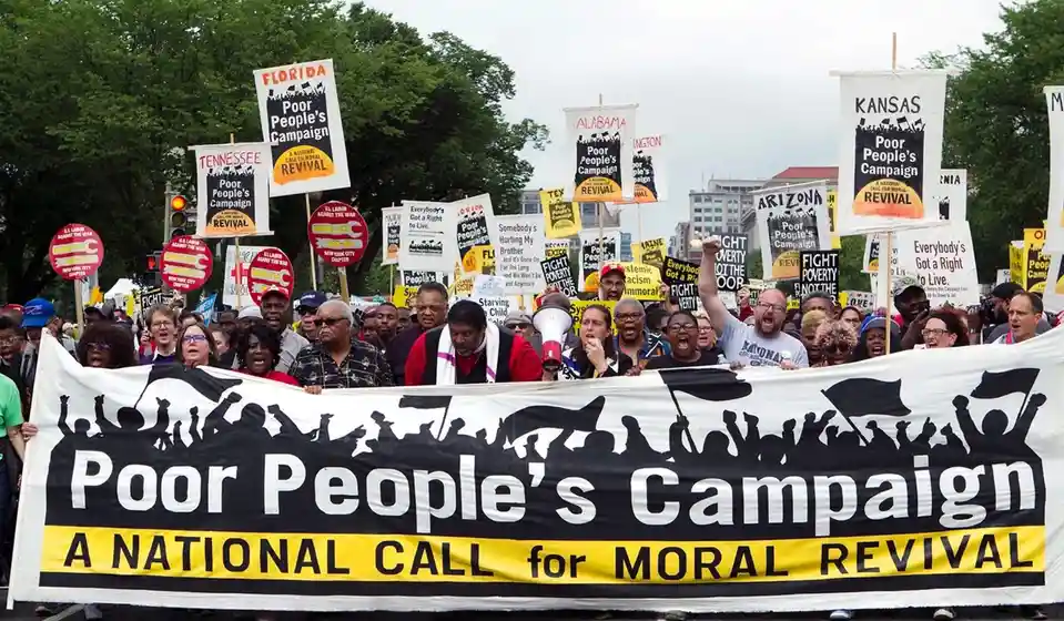 A large crowd of protesters holds signs and a large banner reading 'Poor People's Campaign: A National Call for Moral…