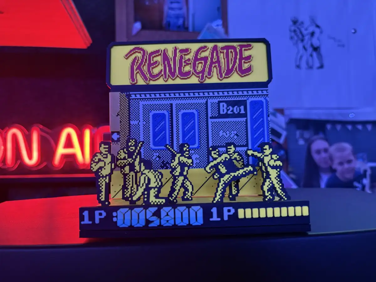 A 3D-printed physical model of the classic arcade game 'Renegade' featuring pixelated characters in combat poses, a yellow…