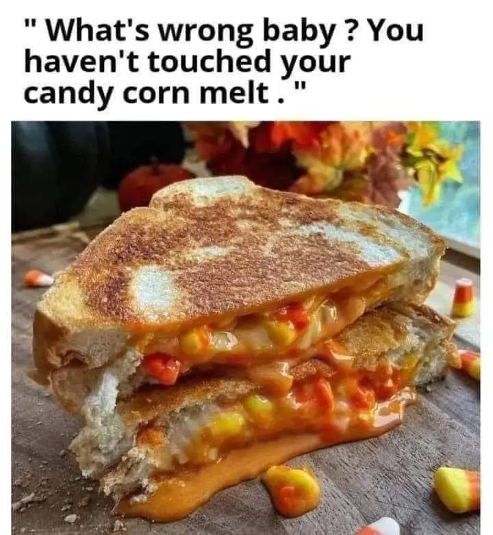 A close-up photo shows a grilled cheese sandwich cut in half, with melted cheese and candy corn pieces oozing out. The…