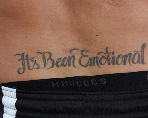 A close-up photo shows a tattoo on a person's lower back that reads 'It's Been Emotional' in cursive script. The tattoo is…