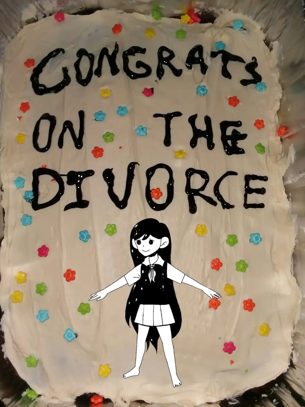 A rectangular cake with white frosting and colorful flower-shaped sprinkles has the message 'CONGRATS ON THE DIVORCE'…
