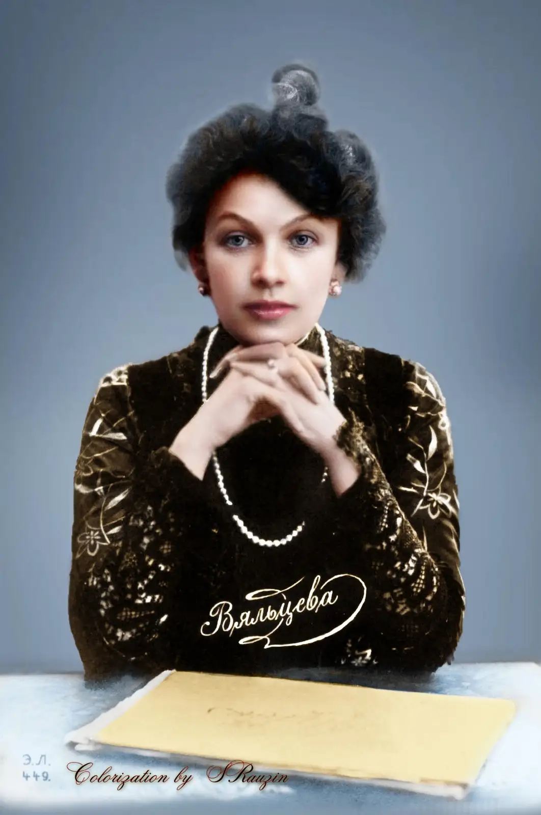 A colorized vintage portrait of a woman with dark curly hair in an updo, wearing a dark velvet dress with floral embroidery…