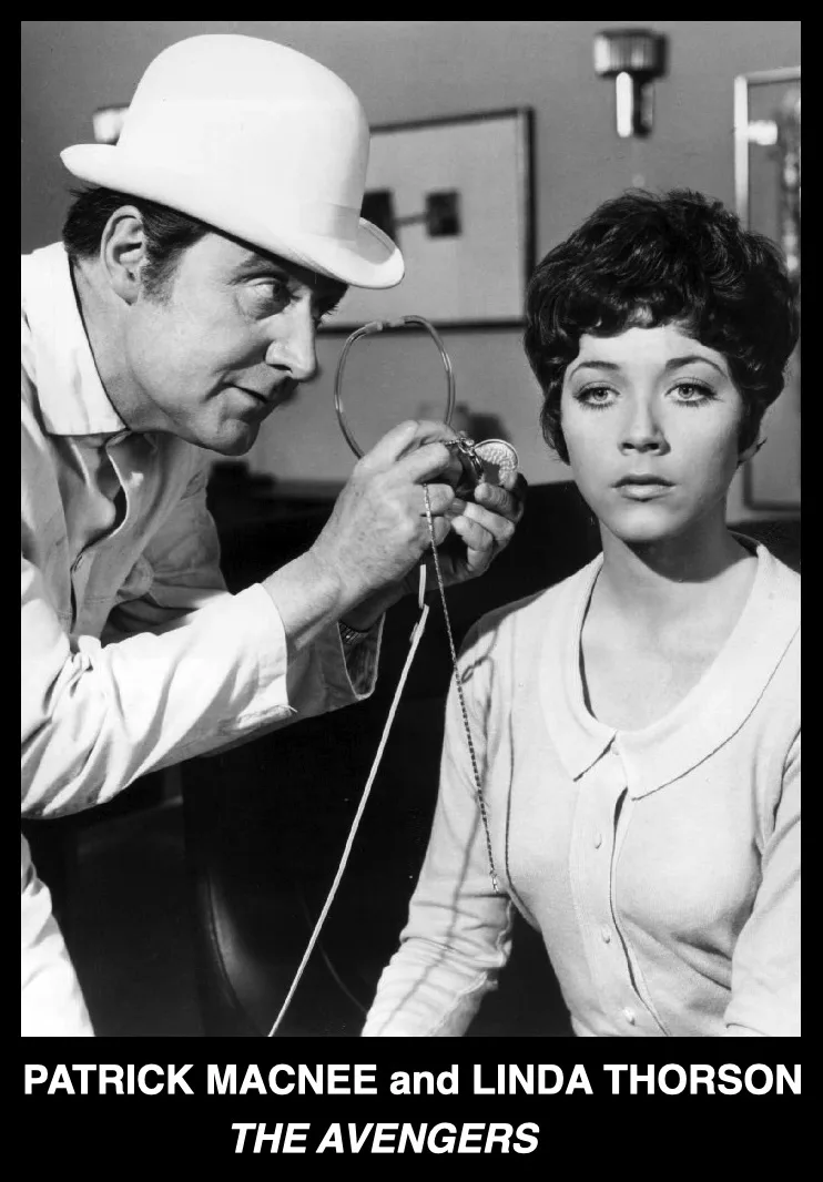 A black-and-white still from the TV show 'The Avengers' shows Patrick Macnee, wearing a white bowler hat and light-colored…