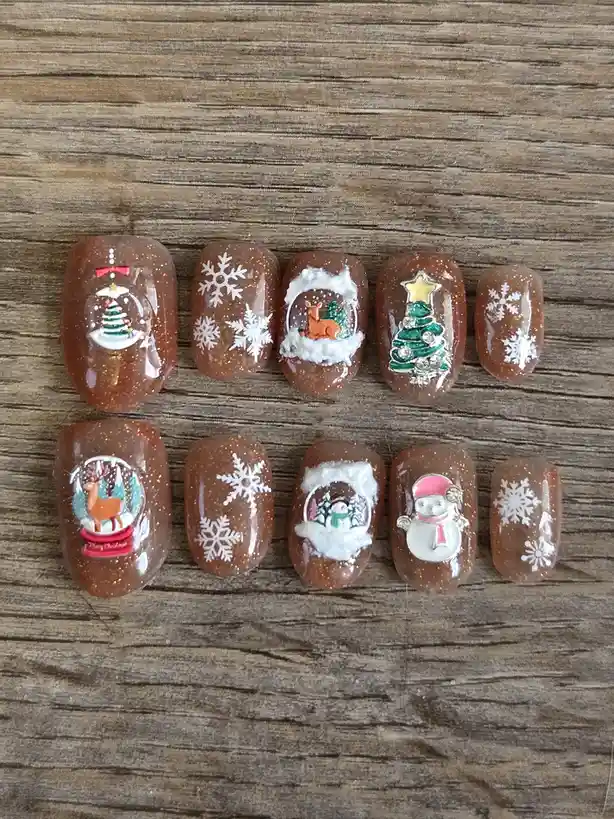 Ten artificial fingernails with glittery brown polish are arranged in two rows on a wooden surface. Each nail features a…