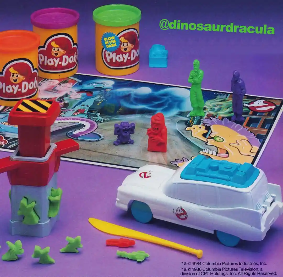 A vintage 1980s Play-Doh advertisement featuring Ghostbusters-themed toys on a purple background. Visible items include…