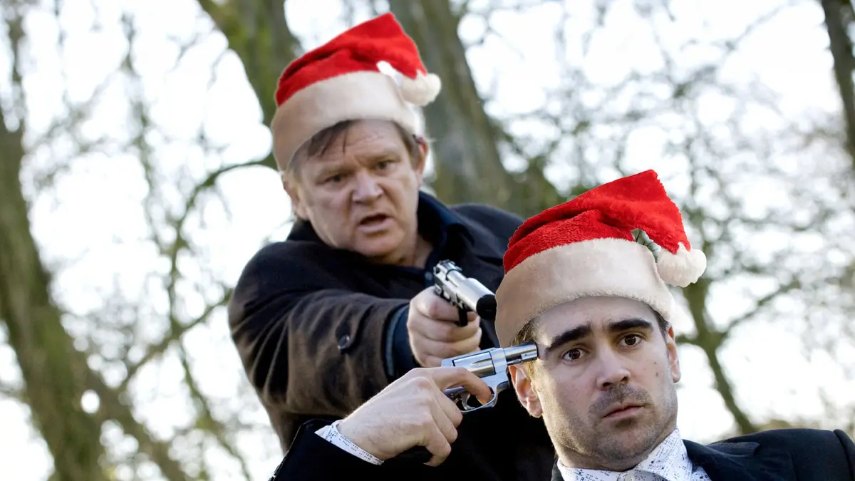Two men wearing red and white Santa hats are shown outdoors with bare trees in the background. The man in the foreground…