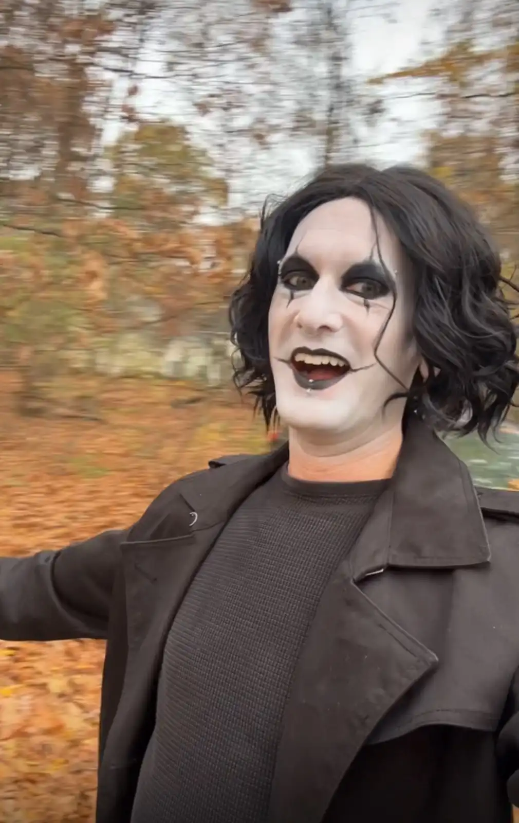 A person with dramatic black-and-white theatrical makeup, including dark eye makeup, black lipstick, and black lines…