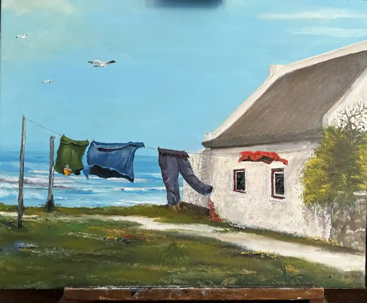 A painting depicts a coastal scene with a white house, laundry hanging on a line, and seagulls flying overhead. The overlaid…