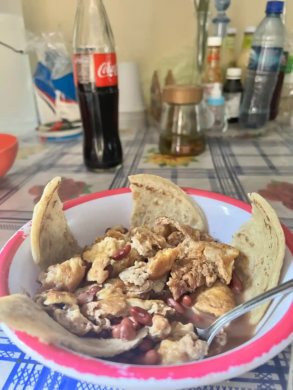 A close-up photo shows a white bowl with a pink rim filled with a meal of scrambled eggs, red kidney beans, and pieces of…