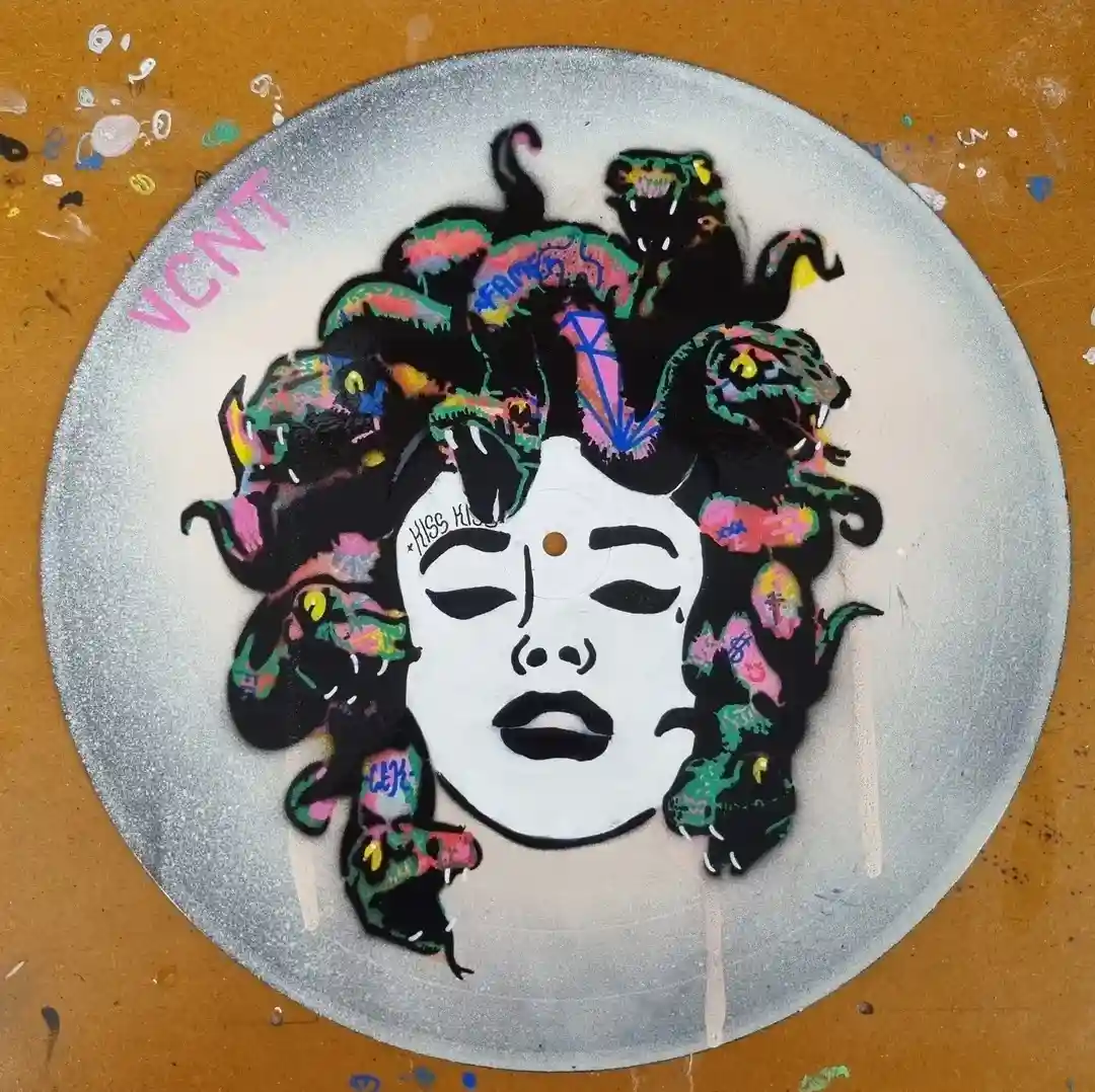 A spray-painted artwork on a vinyl record depicts a stylized Medusa with a white face, black outlines, and multiple…