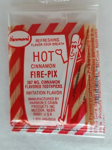 A close-up of a red and white striped package of 'Harmoni Hot Cinnamon Fire-Pix' toothpicks, which are labeled as 'imitation…