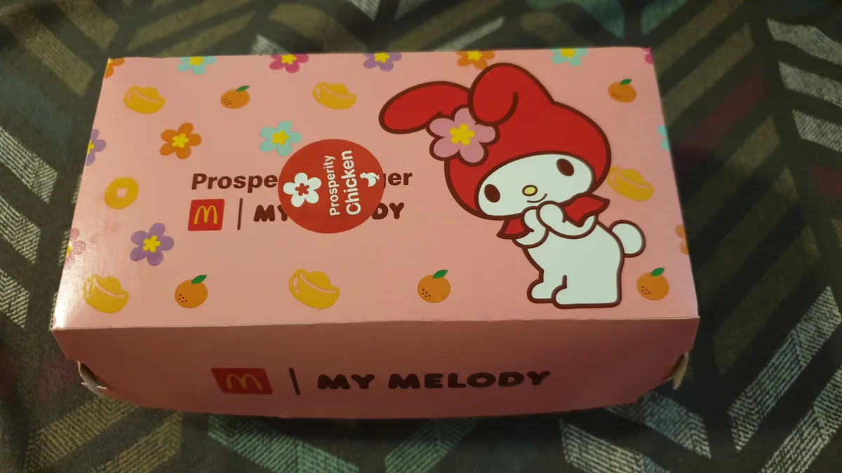 A pink McDonald's chicken meal box features the My Melody character wearing a red hat with a flower, surrounded by floral…