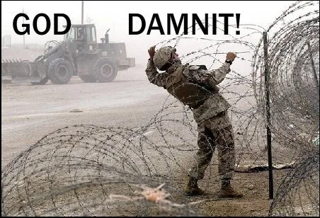 A soldier in camouflage uniform is shown struggling to pull barbed wire, with a large military vehicle visible in the…