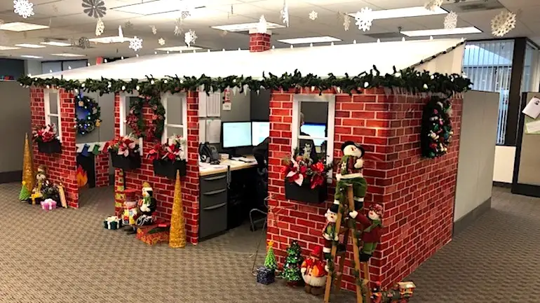 an office cubicle is decorated to look like a christmas cabin with red brick walls, green garland, wreaths, and christmas…