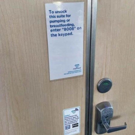 A close-up photo of a light wood-grain door with a digital keypad lock and handle. A white paper sign is taped to the door…