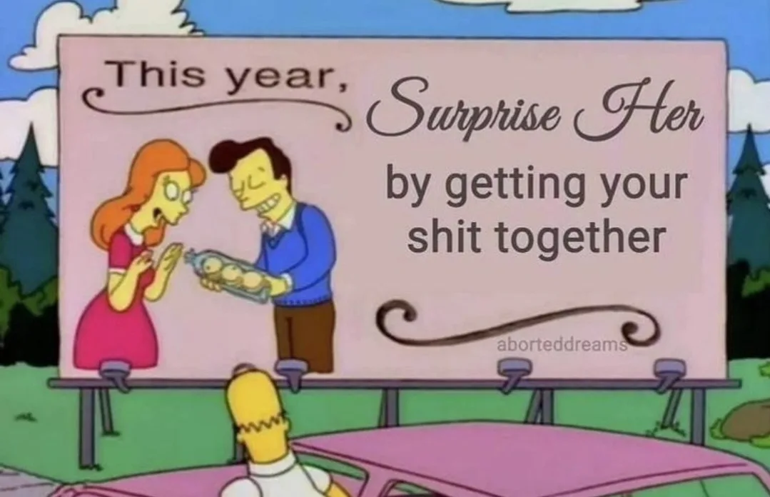 A billboard from The Simpsons shows a man in a blue sweater presenting a baby in a crib to a woman in a pink dress, both…