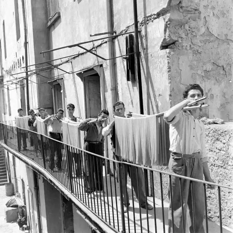 A Glimpse into 1947 Italy: Young Men Drying Pasta