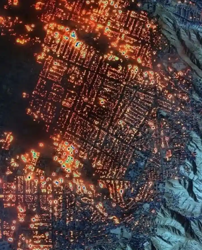 an aerial night view of a sprawling city with countless glowing orange and yellow lights forming a dense grid pattern…