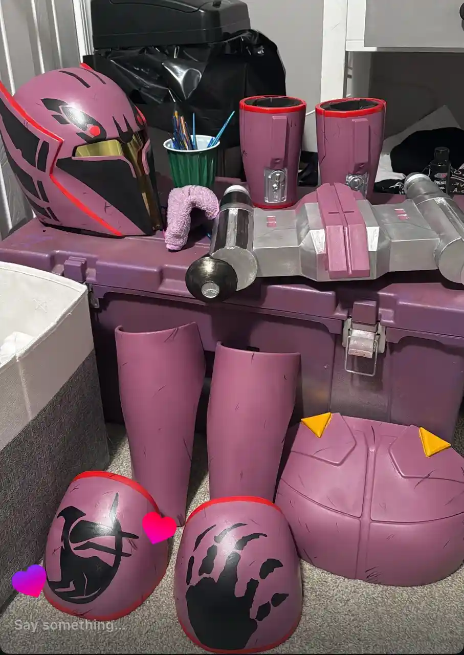 A collection of custom-made purple cosplay armor pieces, including a helmet, gauntlets, greaves, and a chest piece, are…