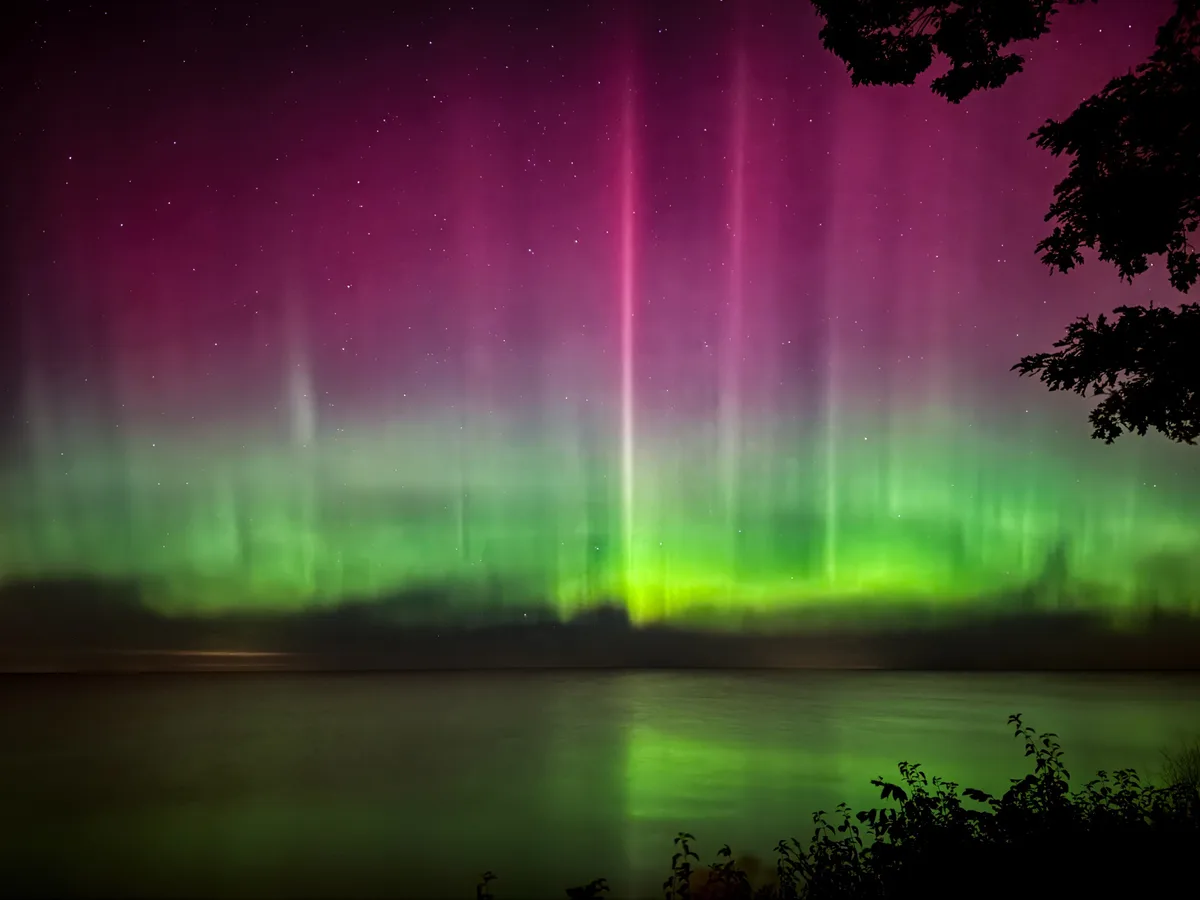 A stunning photograph of the aurora borealis, with vibrant green and magenta light curtains dancing across a starry night…