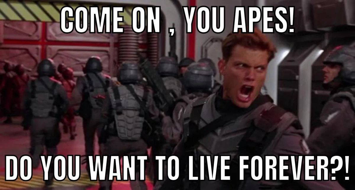 A man in futuristic military gear shouts angrily at a group of similarly dressed soldiers walking away from him. The…