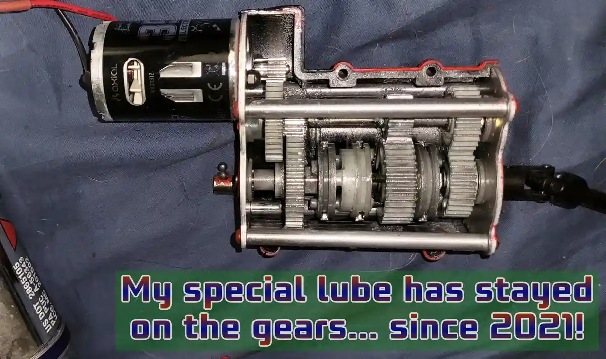 A disassembled mechanical gear box with visible internal gears and a motor, resting on a blue fabric surface. Overlaid text…