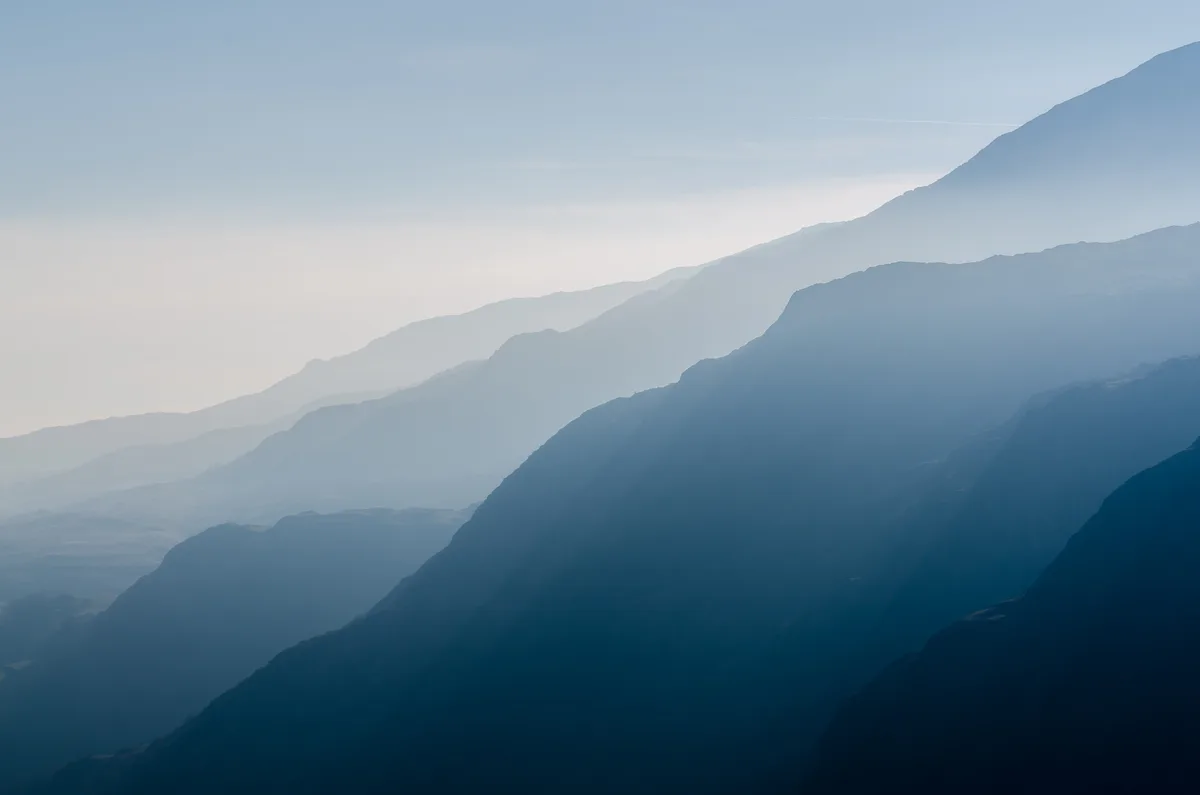 A serene landscape of layered mountain ranges fading into atmospheric haze, with the overlaid text reading 'i'm not lazy…