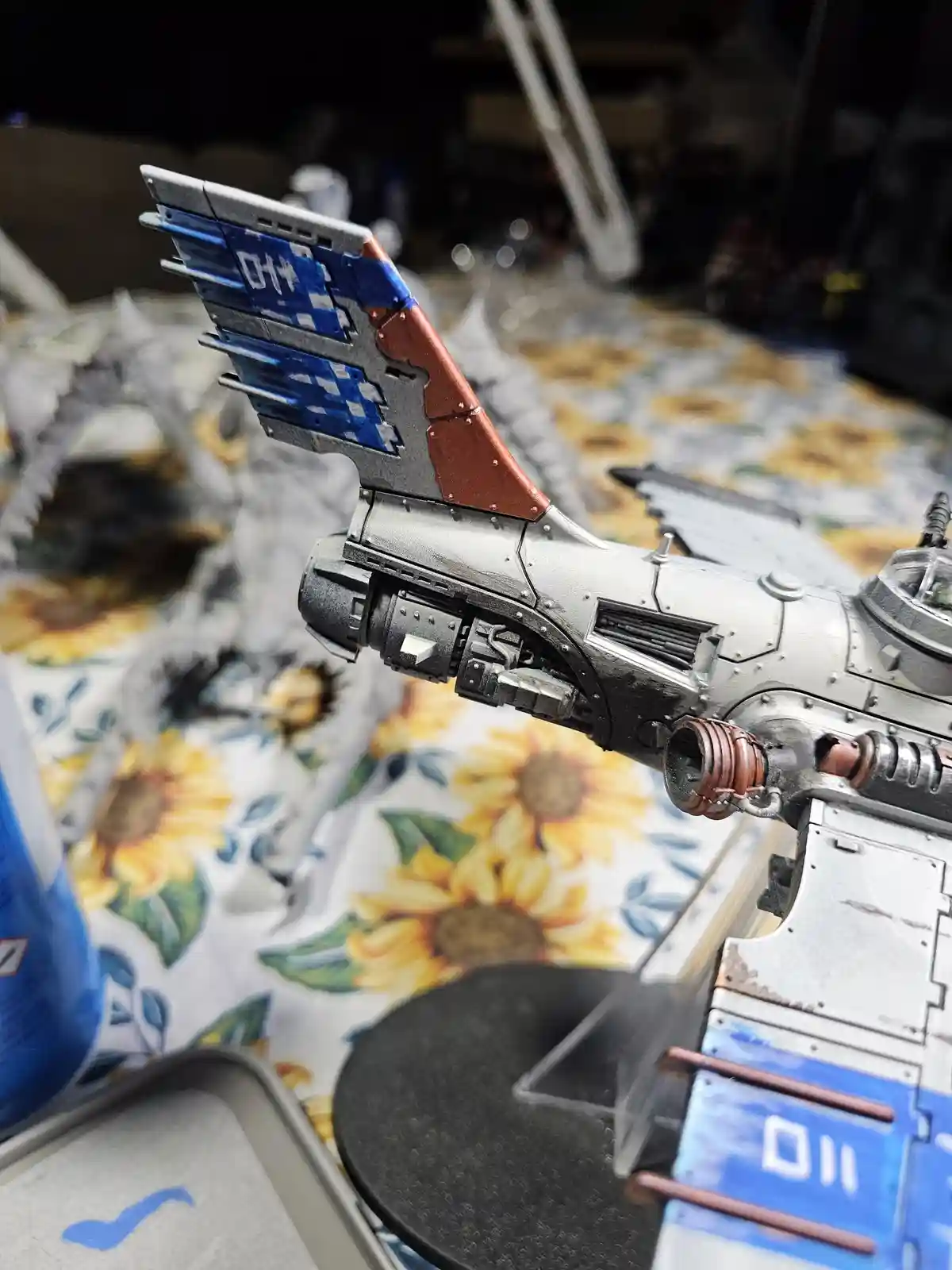 A close-up photo of a detailed, painted miniature spaceship model, likely from Warhammer 40,000, resting on a…